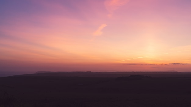 Imagem horizontal de um campo sob um céu roxo de tirar o fôlego