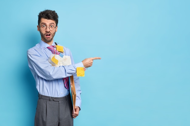 Foto grátis imagem horizontal de um estudante inteligente surpreso cercado de papéis vestidos com roupas formais dá pontos de ideias de inicialização no espaço da cópia