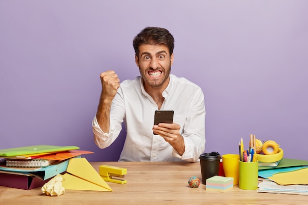 Imagem horizontal de um funcionário irritado sentado na mesa do escritório