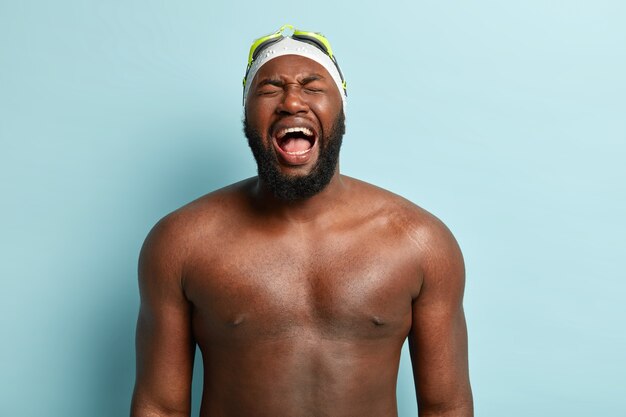 Imagem horizontal de um homem afro-americano superemotivo com um corpo forte e nu, grita emocionalmente