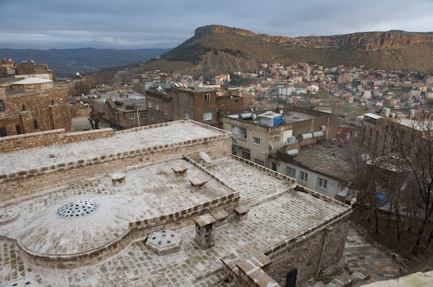 Imagem horizontal de uma cidade no sopé de uma colina com edifícios antigos