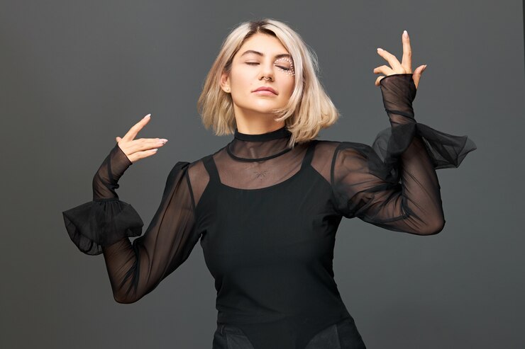 Foto grátis imagem isolada de linda jovem loira movendo as mãos em sintonia com a música em um show ou performance, festejando com amigos, curtindo a liberdade, tendo uma expressão facial alegre e feliz