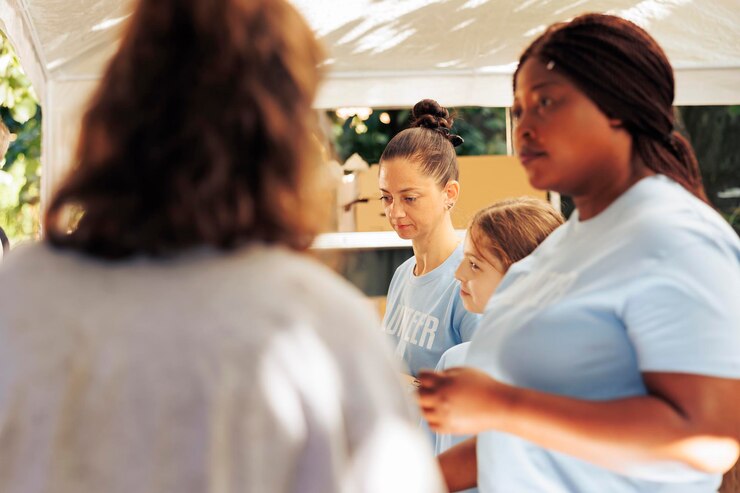 Foto grátis imagem que mostra uma equipe voluntária feminina em um centro de caridade distribuindo comida de graça entre os menos privilegiados da vizinhança. são vistos indivíduos voluntários ajudando os pobres e os sem-teto.