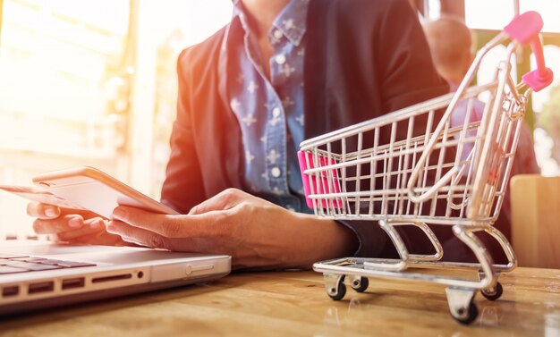 Imagem recortada da mulher que fornece informações sobre cartões e chave no telefone ou laptop enquanto faz compras on-line.