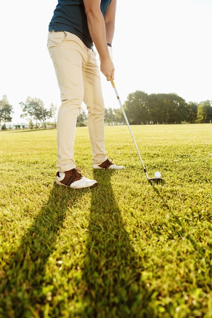 Imagem recortada de um jogador de golfe colocando a bola de golfe no verde