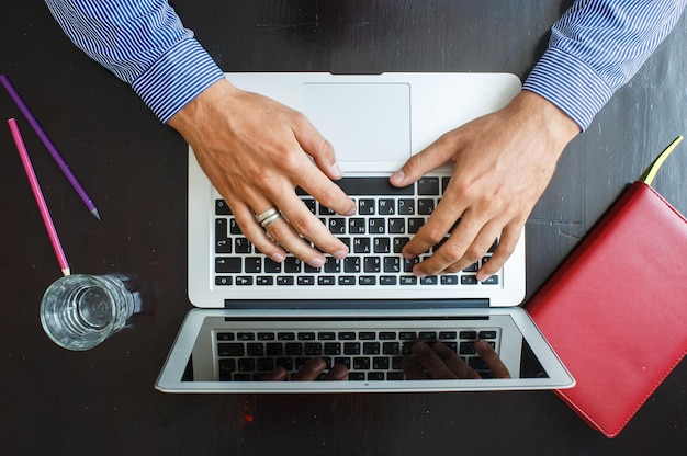 Foto grátis imagem recortada de um jovem trabalhando em seu laptop em casa vista superior das mãos de homem de negócios ocupadas usando laptop na mesa de escritório