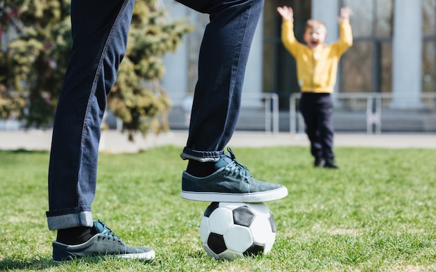 Imagem recortada de um pai jogando futebol com seu filho