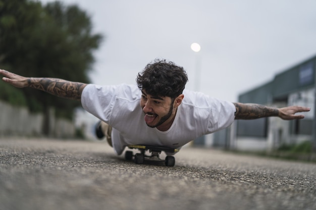 Imagem superficial de um europeu sorridente e bonito deitado em um skate