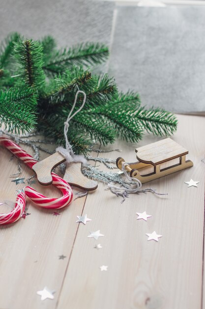 Imagem vertical de bastões de doces e decorações de Natal em uma mesa de madeira sob as luzes