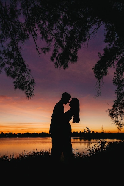 Imagem vertical de belas silhuetas de amantes contra um céu hipnotizante