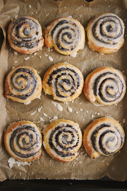 Imagem vertical de deliciosos pastéis de caracol poppy com cobertura de açúcar em uma bandeja na mesa de madeira