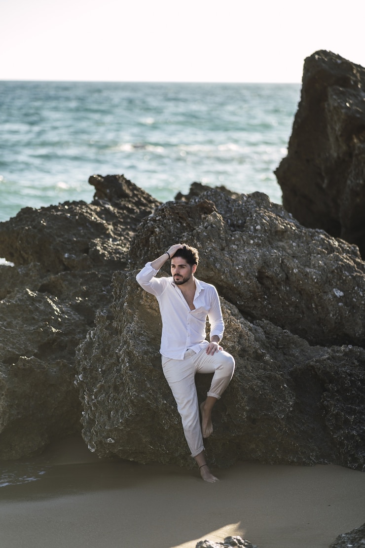 Foto grátis imagem vertical de um homem moreno encostado na rocha e posando