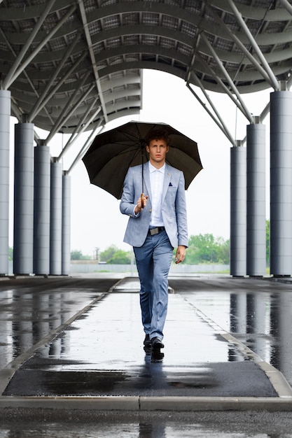 Imagens do jovem empresário ruivo segurando guarda-chuva andando na rua