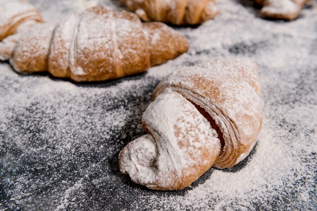 Imagens macro de croissants com açúcar de confeiteiro na tabela cinza.