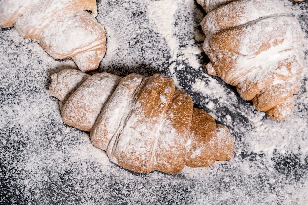 Imagens macro de croissants com açúcar de confeiteiro na tabela cinza.
