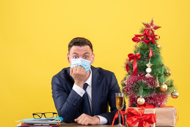 imaginou o homem sentado à mesa perto da árvore de natal e presentes em amarelo