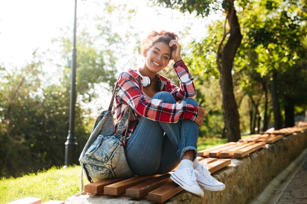 Incrível jovem mulher africana sentada ao ar livre no parque