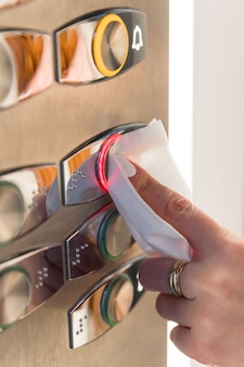 Indicador de mulher pressionando o botão vermelho no elevador através de um guardanapo