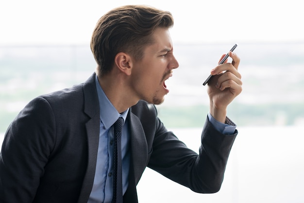 Indignado adulto homem de negócios irritado em smartphone