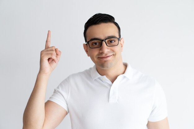 Indivíduo novo de sorriso que aponta para cima e que olha a câmera.