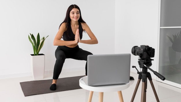 Influenciadora feminina em casa fazendo vlogs enquanto se exercita