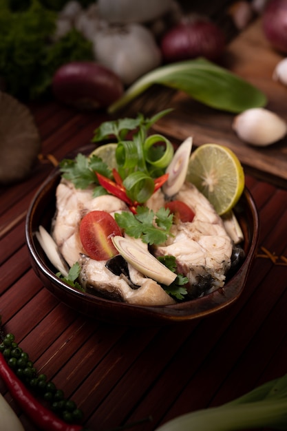 Foto grátis infusão de peixe cozido com tomate, cogumelos, coentro, cebolinha e capim-limão em uma tigela