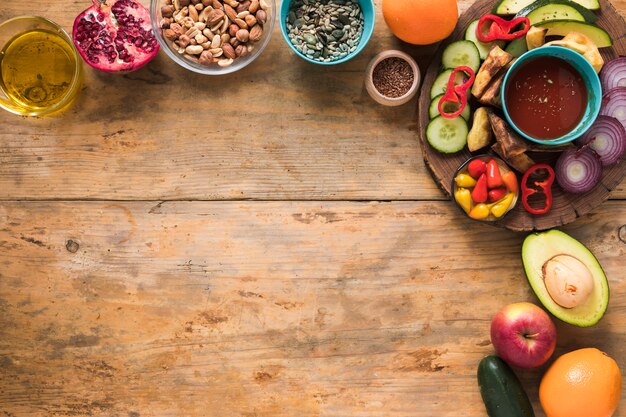 Ingredientes; frutas secas; frutas; óleo e legumes fatiados na mesa de madeira