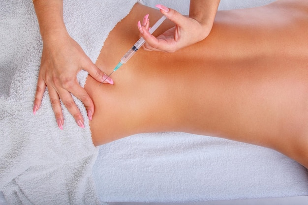 Injeção de seringa nas costas da mulher. Mulher desfrutando de massagem relaxante nas costas no centro de spa de cosmetologia.