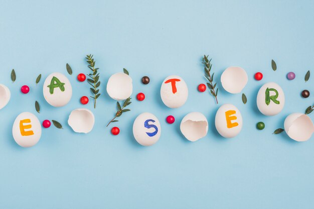 Foto grátis inscrição de páscoa em ovos com galhos de plantas na mesa