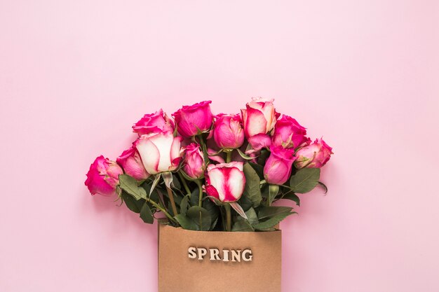 Inscrição de primavera em saco de papel com rosas