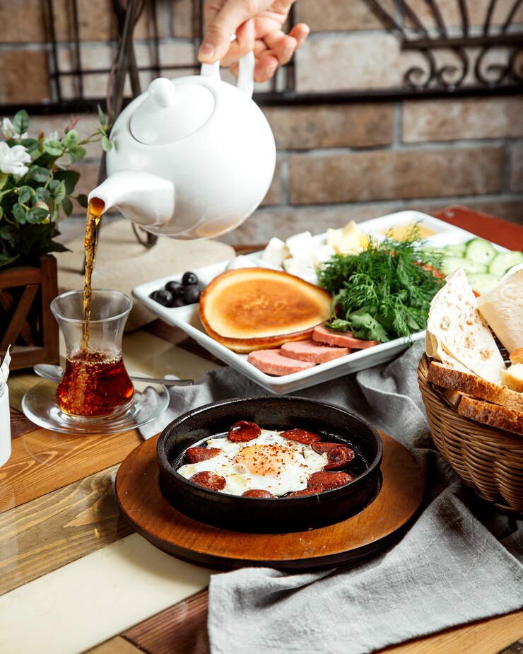 Foto grátis instalação de café da manhã com ovo com salsichas panqueca ervas queijo legumes e chá
