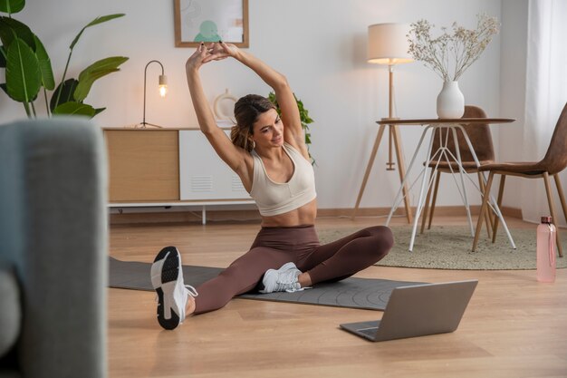 Instrutor de fitness feminino usando laptop para dar uma aula em casa