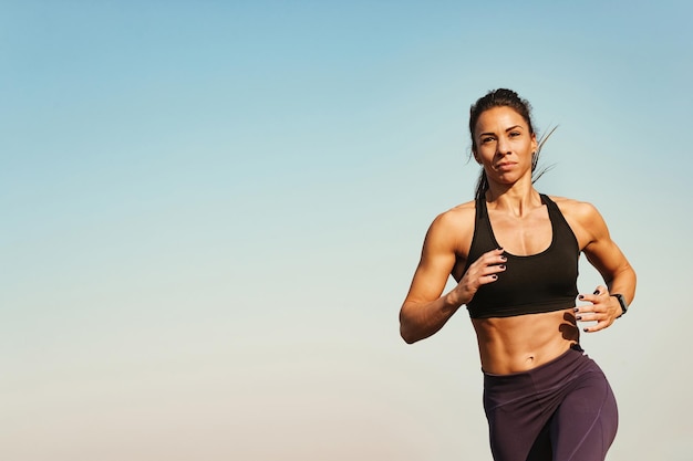 Foto grátis instrutor de fitness jovem se sentindo motivado enquanto corre contra o céu copie o espaço