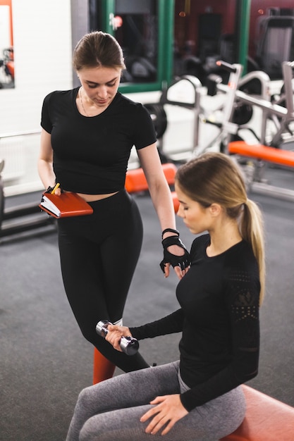 Foto grátis instrutor de ginástica orientando a mulher durante o exercício com halteres