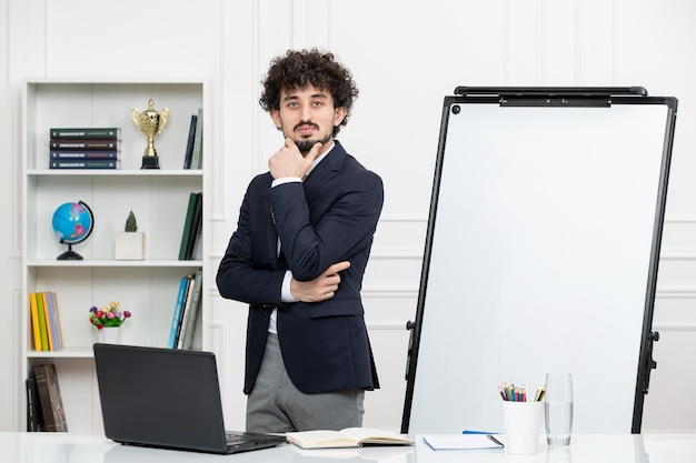 Instrutor moreno professor com computador de terno e quadro branco em sala de aula parado