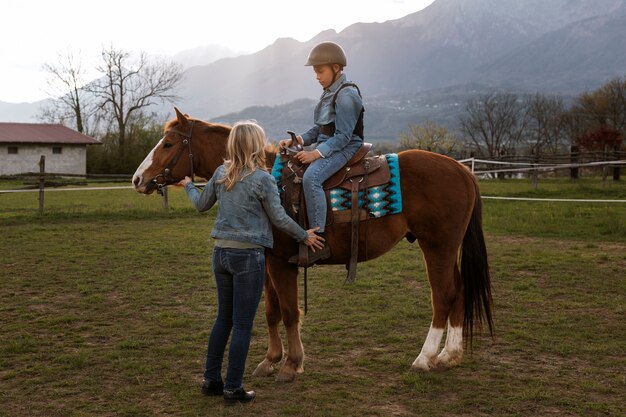 Instrutora equestre feminina ensinando criança a andar a cavalo