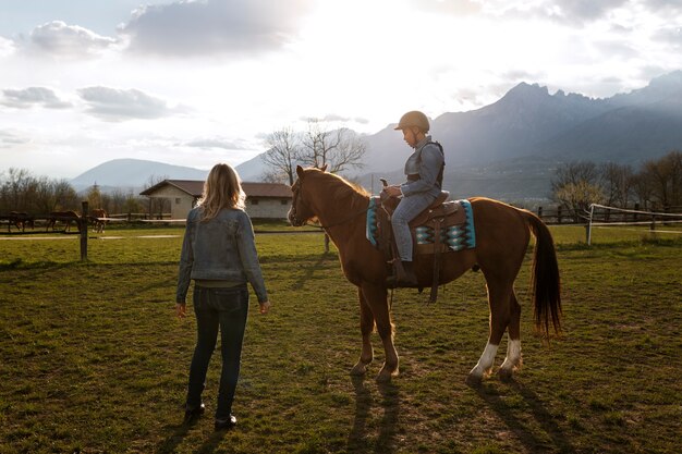 Instrutora equestre feminina ensinando criança a andar a cavalo