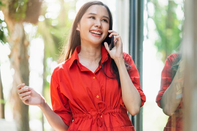 Inteligente bonito atraente asiático feminino cabelo comprido sorriso mão segure smartphone comunicação social conectando ideias conceito borrão bokeh jardim backgroundasia mulher sorrindo andar perto de grande janela café