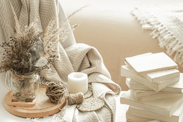 Interior aconchegante da sala com livros e flores secas em um vaso.