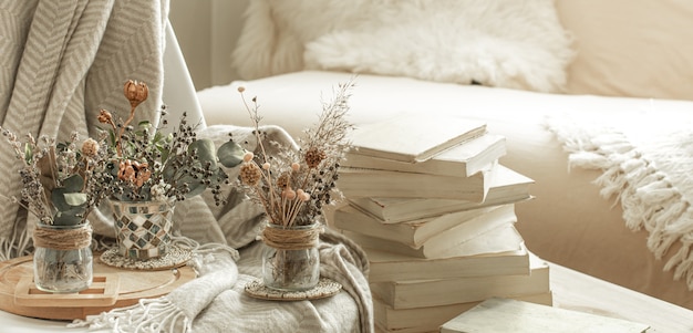 Interior aconchegante da sala com livros e flores secas em um vaso.