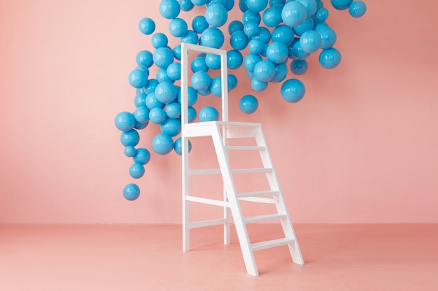 Interior brilhante cor-de-rosa do estúdio com escada branca e bolas azuis de suspensão.