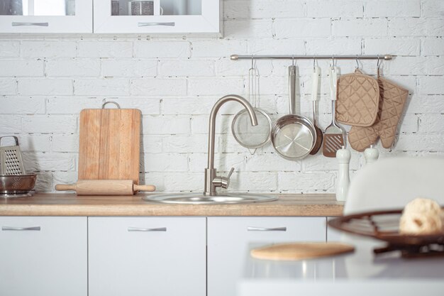 Interior de cozinha escandinavo moderno e elegante com acessórios de cozinha. Cozinha branca brilhante com utensílios domésticos.