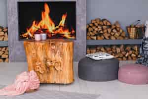 Foto grátis interior escandinavo com uma lareira, mesa de coto, uma pilha de toras para fogo