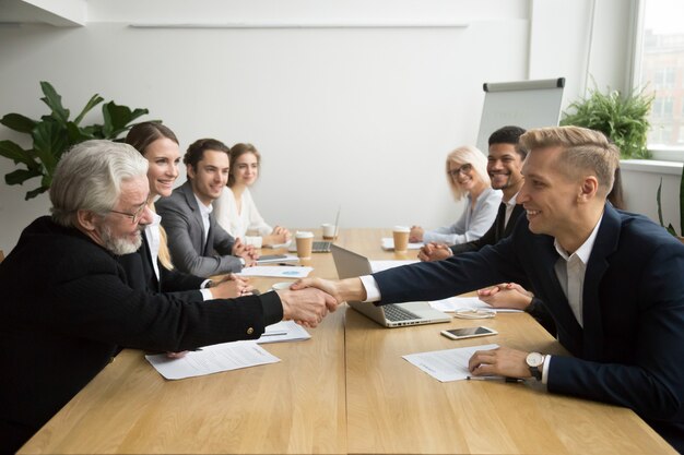 Investidor sênior, comprando, startup, handshaking, jovem, empreendedor, em, reunião grupo