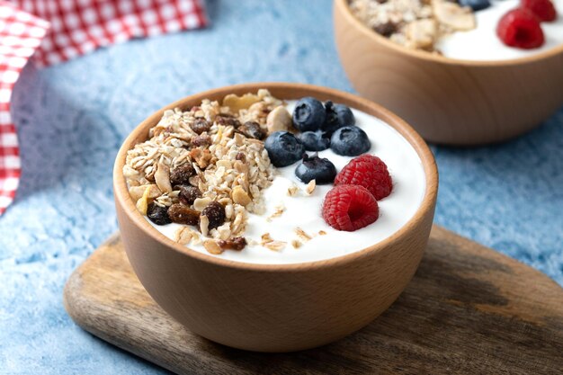 Iogurte com frutas e muesli no café da manhã na tigela sobre fundo azul