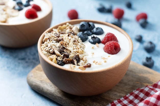 Foto grátis iogurte com frutas e muesli no café da manhã na tigela sobre fundo azul