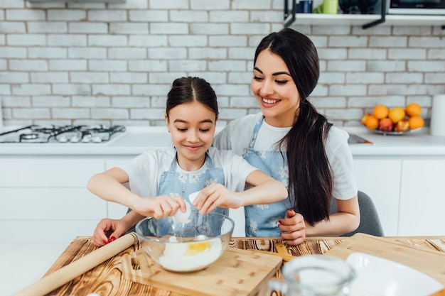 Irmã mais velha sorridente com sua menor. cozinhe com ovos