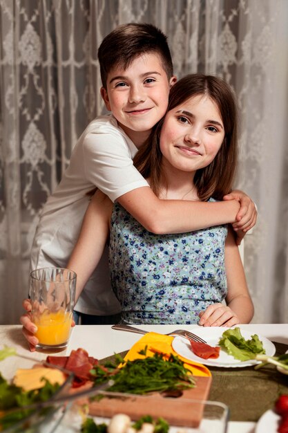 Irmão e irmã abraçados na mesa de jantar