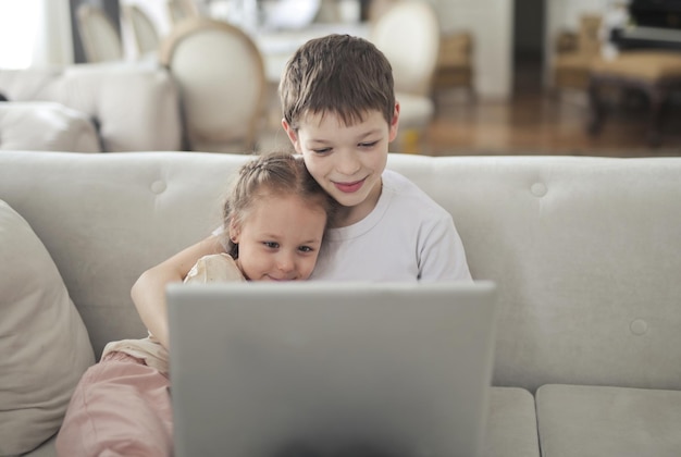 irmão e irmã usam um computador sentado no sofá