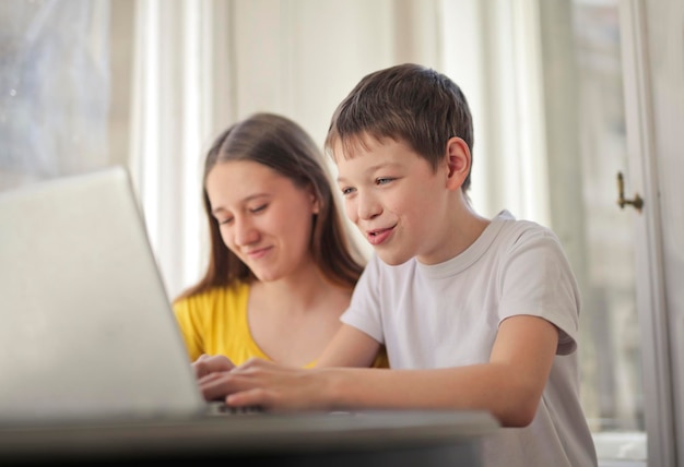 Irmão e irmãs trabalham com um laptop